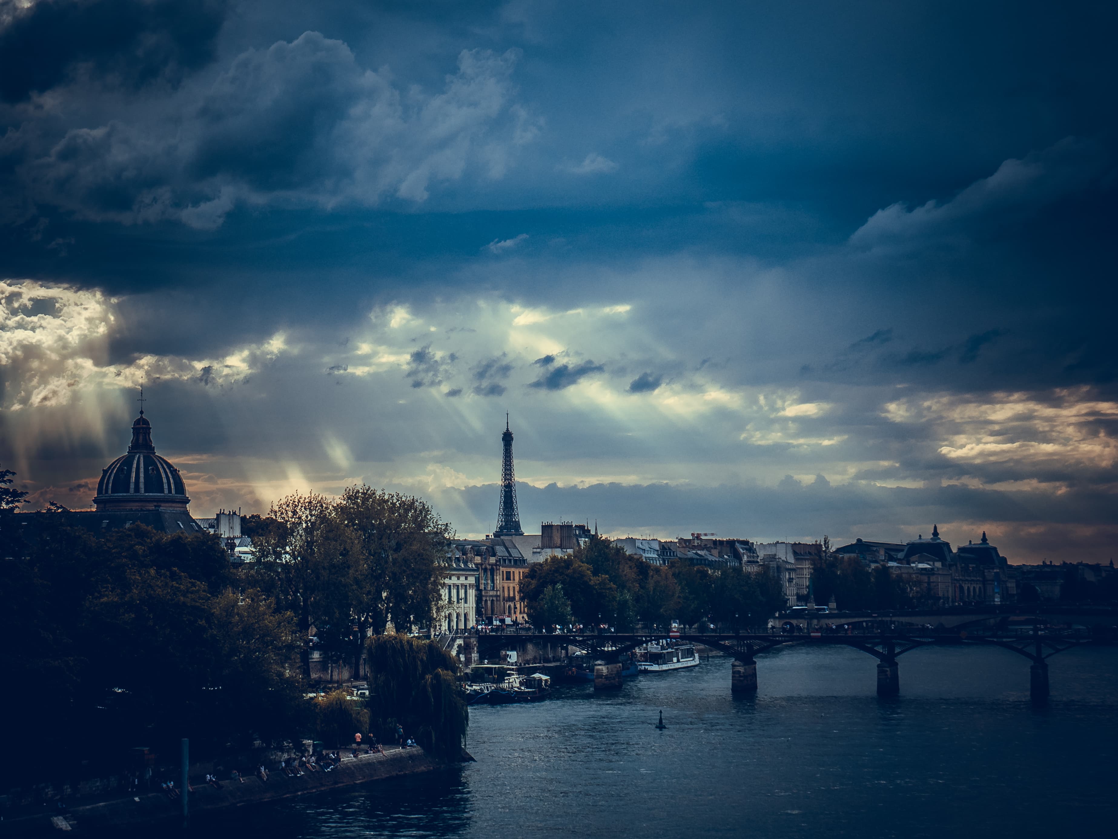 The Eiffel Tower seen across the River Seine beneath dramatic evening clouds