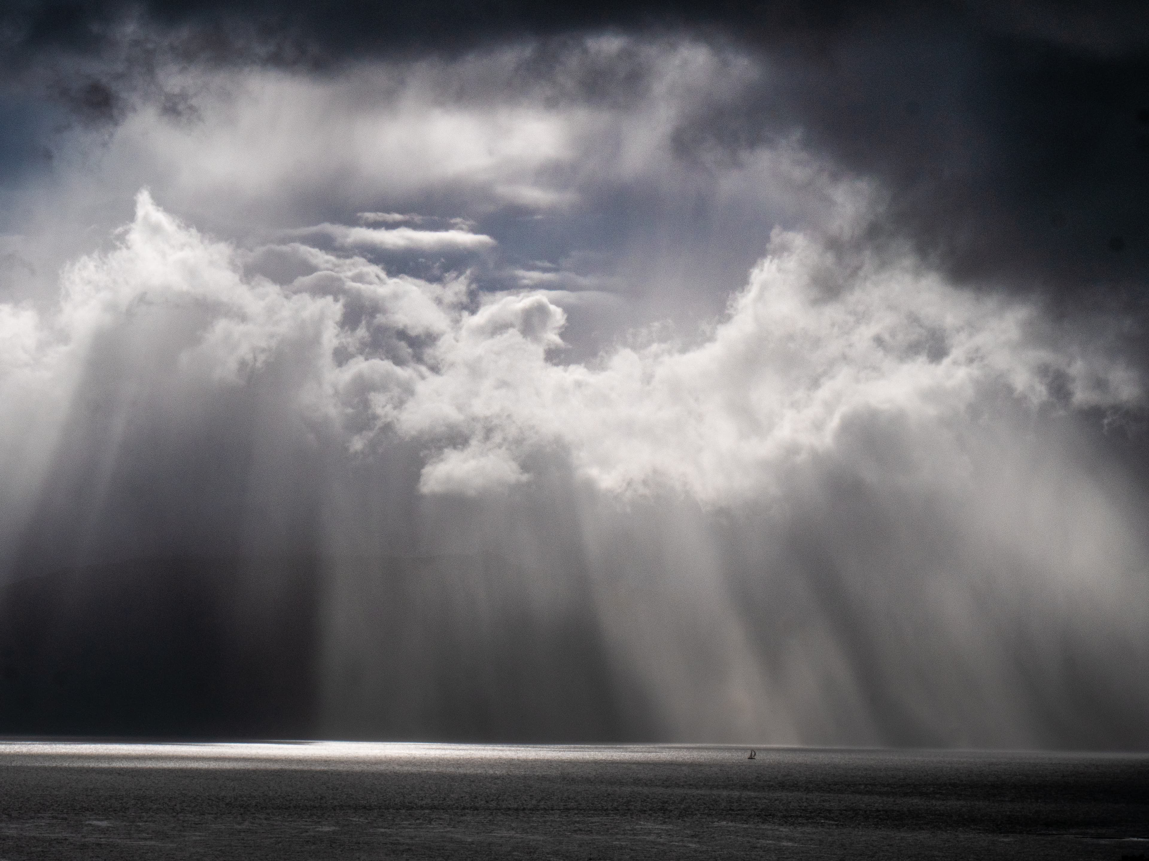 Sunlight breaking through dramatic storm clouds over the Scottish landscape